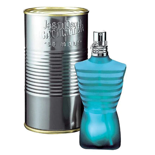 Jean Paul Gaultier Le Male perfume bottle in a distinctive turquoise blue ribbed shape next to its signature silver tin packaging with gold trim.